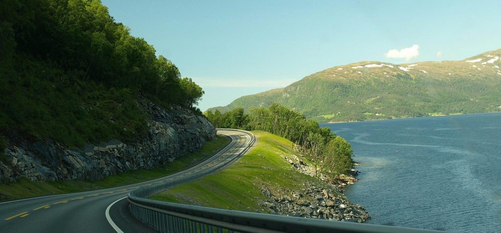 Road by a lake in Europe to illustrate car vs train in Europe