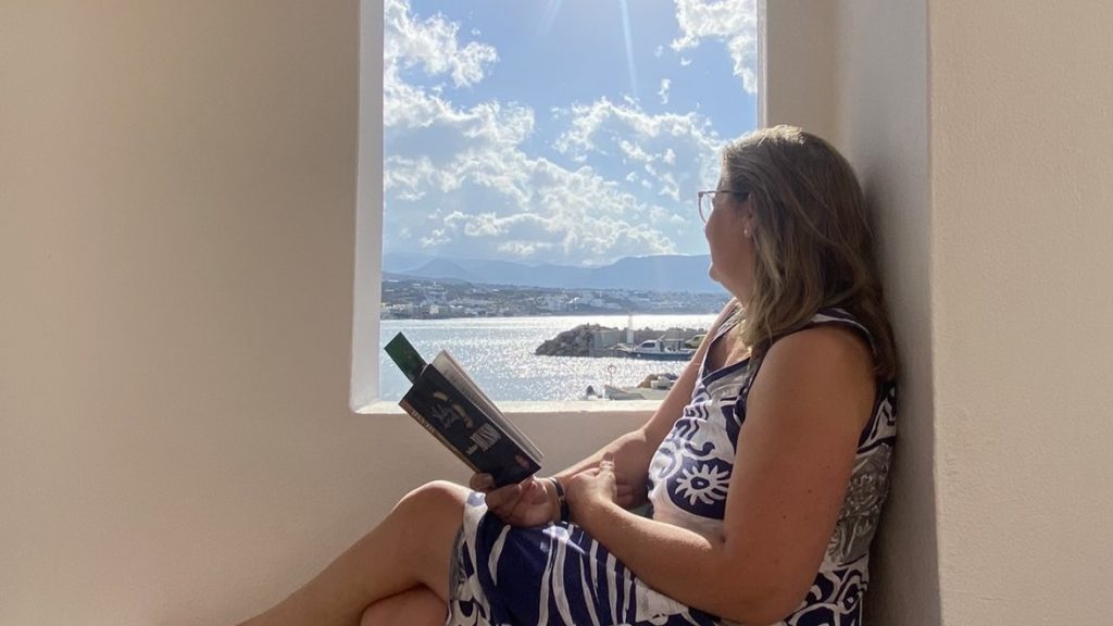 Reading a book with a view over the harbour Makry Gialos